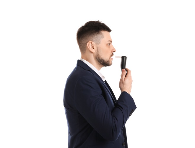 Man blowing into breathalyzer on white background